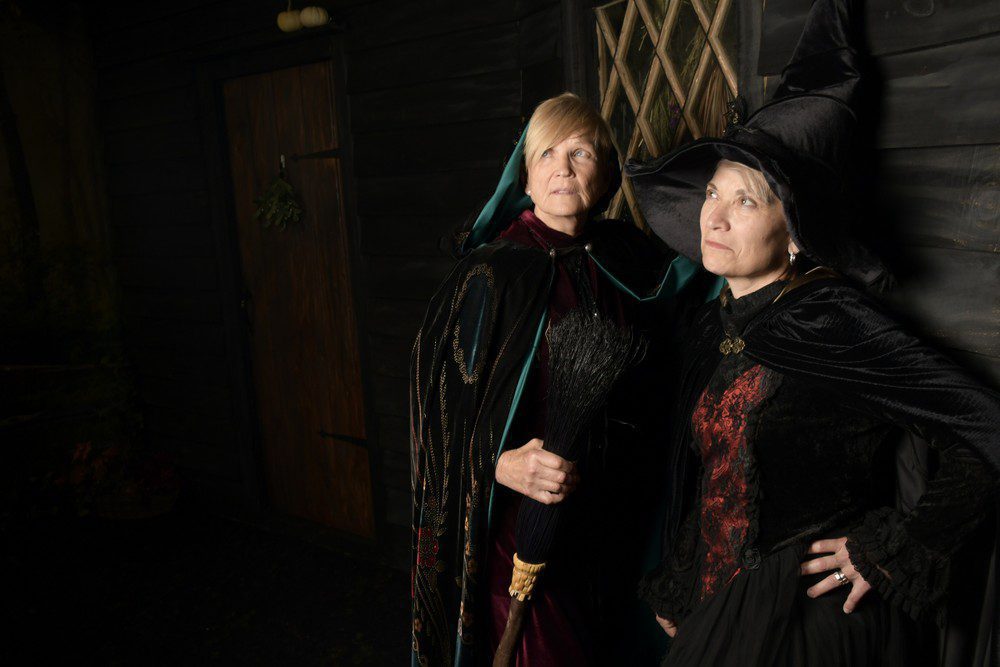 two women dress as witches and look into the distance